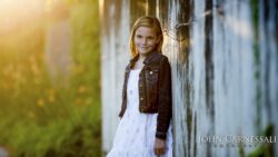 Young girl standing by a wooden wall