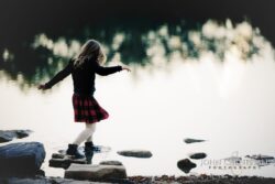 Little girl standing on rocks by the water