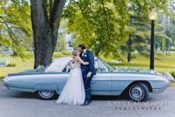 bride and groom pose by classic car on their wedding day