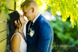 Bride and groom standing close together by a wall
